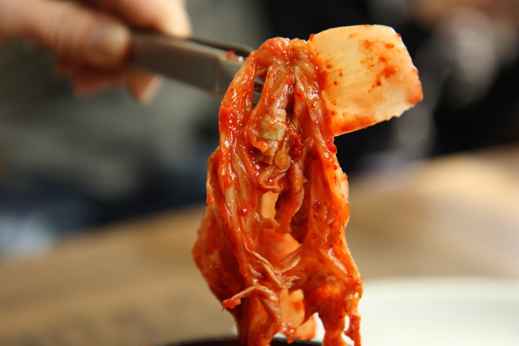 kimchi wordt omhoog gehouden met een tang